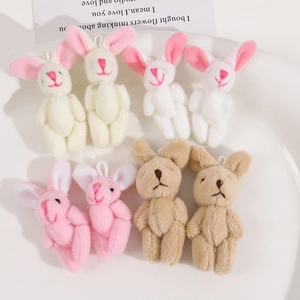 Detail view of colorful plush bunny charms in white, pink, and tan with cute embroidery