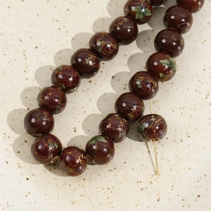 Close-up of 12mm hand-painted ceramic beads with vintage floral patterns in a tray