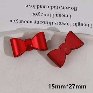 Macro detail of red bow resin charm with 15mm by 27mm dimensions on ceramic plate