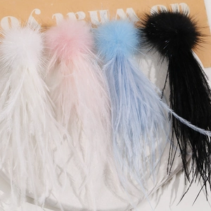 Macro view of long feather tassel ornaments in white, pink, blue and black on marble