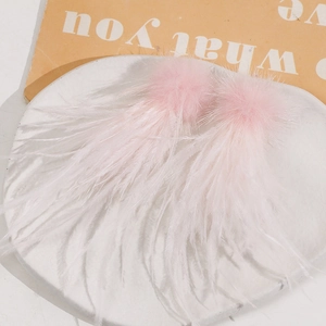 Chic pink feather tassels with fluffy pom-poms on a white display tray for DIY accessories
