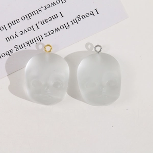 Macro shot of matte translucent doll head resin pendants with gold and silver metal loops