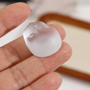Close-up of matte translucent face charm for DIY jewelry held between fingers