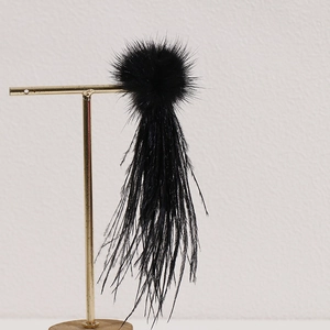 Detail of long black feather tassel ornament with soft faux fur pom-pom on gold stand