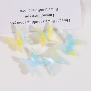 Detail view of 5 marble patterned butterfly charms with blue and yellow ink textures