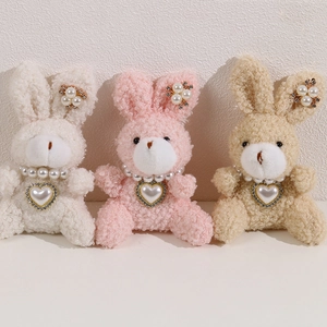 Detailed close-up of plush rabbit dolls in pink and white with pearl and rhinestone accents