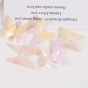 Flat lay of five gradient resin butterfly charms for DIY phone case accessories
