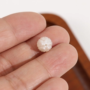 Vue macro d'une perle tulipe blanche sculptée montrant la texture florale pour bijoux DIY