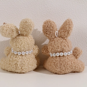 Detail view of plush bunny figures with curly faux fur and white pearl necklaces