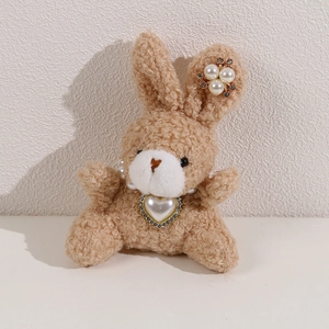 Detail of light brown curly plush bunny with pearl heart necklace and rhinestone ear decor