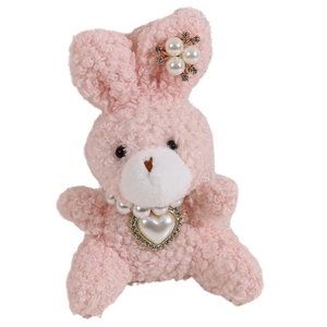 Pink plush bunny doll with pearl necklace and large heart pendant on white background