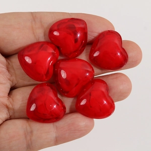 Vue macro de six cœurs en résine rouge translucide tenus à la main pour bijoux DIY