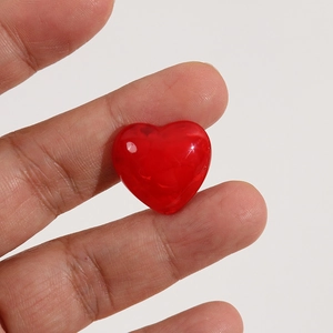 Gros plan de petits charms en forme de cœur rouge en résine pour bijoux et nail art