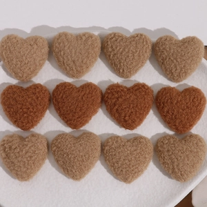 Macro view of plush lamb wool heart patches for DIY accessories in brown and khaki tones