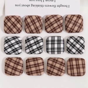 Macro detail of square fabric buttons in brown and black-white checkered patterns
