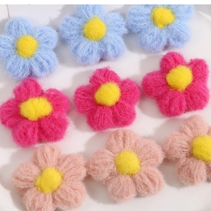 Detailed texture of handmade knit puff flower accessories in sky blue, rose, and pink colors