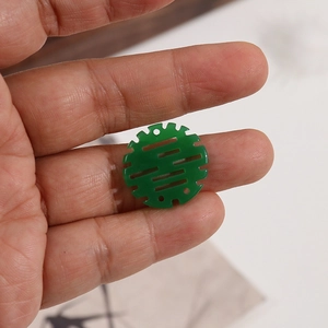 Dettaglio macro di un ciondolo in resina traslucida verde con motivi cinesi tradizionali