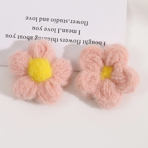 Detail showing two handmade crochet 3D pink and yellow puff flowers with soft wool texture