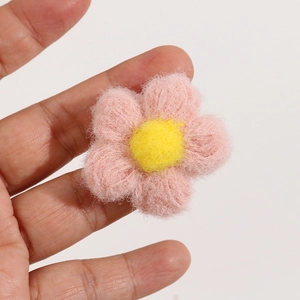 Close-up of handmade pink and yellow wool felt puff flower for DIY accessories