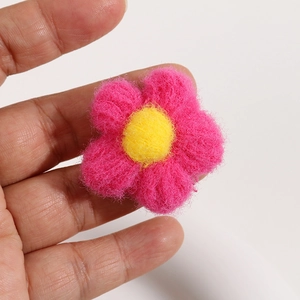 Macro shot of handmade pink puffed yarn flower with yellow core for DIY hair accessories