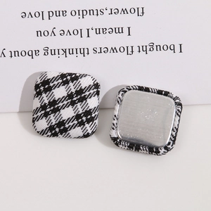 Detailed view of square fabric buttons with black and white checkered pattern and metal back