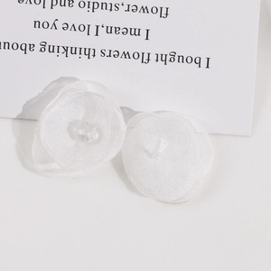 Detailed view of delicate white mesh petal flowers with center bead for DIY jewelry