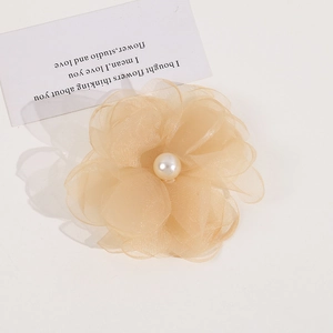 Detail of a layered organza flower clip with a center pearl on an elegant white background