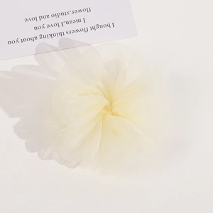 Detailed view of layered light yellow organza mesh flower hair tie on white card