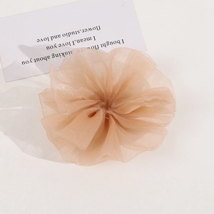 Close-up of a ruffled beige mesh flower scrunchie with layered texture and soft airy fabric