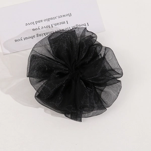 Macro detail of large black pleated mesh floral hair accessory with layered gauze texture