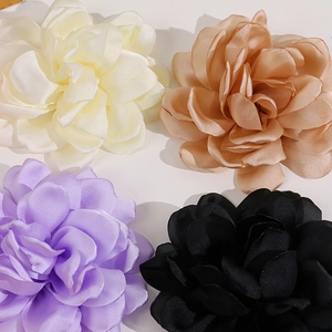 Macro detail of multi-layered satin camellia flowers in cream, champagne, and black colors