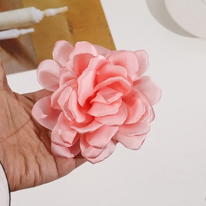 Detailed view of large pink satin fabric camellia flower for DIY hair accessories