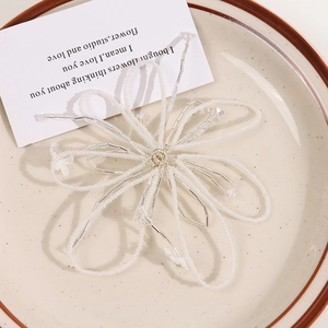 Exquisite handmade beaded flower hair clip with white pearls and glass beads on a ceramic plate