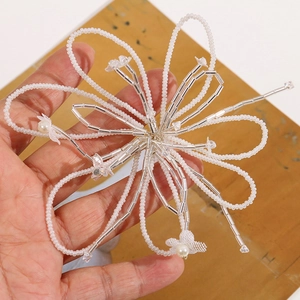 Close-up of handmade white glass beaded flower hair accessory with detailed weaving