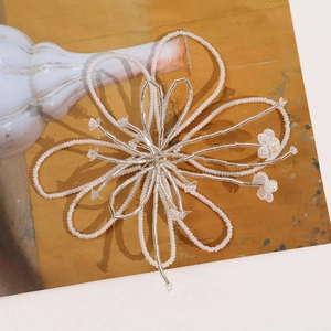 Detail of handcrafted oversized white floral bead ornament with silver glass accents
