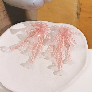 Macro detail of pink glass beaded lily of the valley tassel earrings on ceramic plate