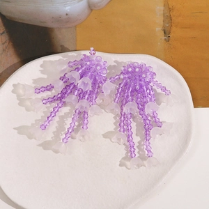 Detail of handmade purple lily of the valley earrings with beads on a ceramic tray