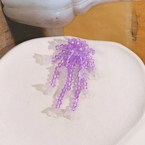 Detailed view of handmade purple beaded lily of the valley tassels in a ceramic dish