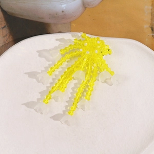 Macro detail of handmade yellow glass bead tassels with white lily of the valley flowers