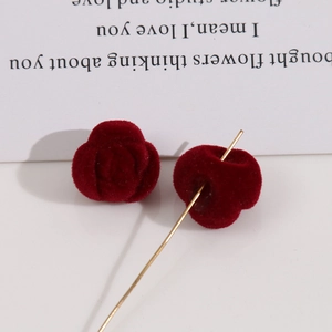 Vue macro montrant la texture veloutée et l'aiguille dorée de l'accessoire rose rouge