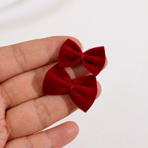 Detailed macro view of two handmade burgundy velvet bow hair accessories on a white background