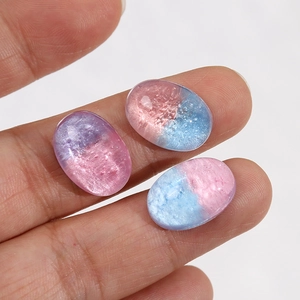 Macro detail of colorful glitter resin oval cabochons for DIY accessories held on a fingertip