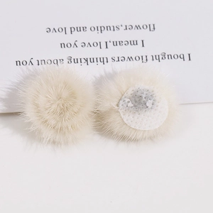 Detailweergave van 3 cm crème pluche pompons met bovenkant van bont en bevestigingsbasis