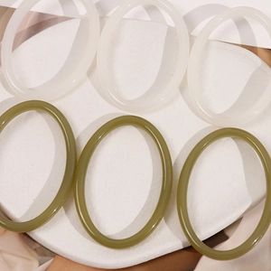 Close-up of geometric resin hollow earrings in translucent cream and olive green