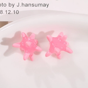Pink sea urchin star stud earrings with a glossy mirror finish on white ceramic