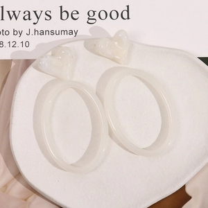Detail of cream white minimalist resin earrings featuring a heart and oval hoop design