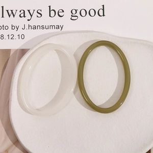 Close-up of translucent frosted white and olive green oval resin earrings on a dish
