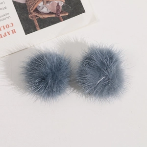 Detailansicht zweier graublauer Webpelz-Pompons für DIY-Haarschmuck und Bastelbedarf