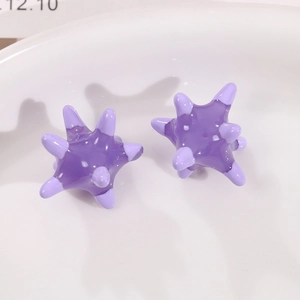 Macro shot of purple star-shaped acrylic earring components in a white ceramic dish