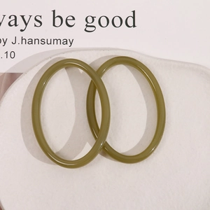 Detailed view of olive green resin hoop earrings on a textured white stone tray